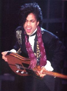 an image of a man that is holding a guitar in his hand and wearing a scarf around his neck