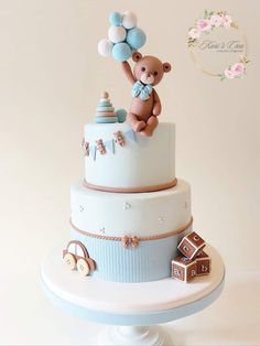 a baby shower cake with a teddy bear on top and balloons in the air above it