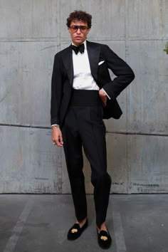 a man in a tuxedo standing next to a wall