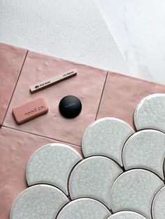 a pink and white tiled floor with various items on it, including a pen, eraser, and pencil