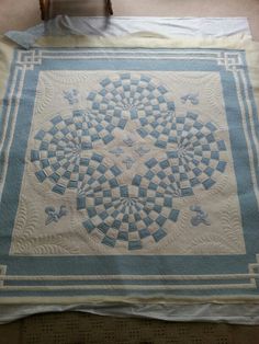 a blue and white quilt sitting on top of a bed next to a wooden chair