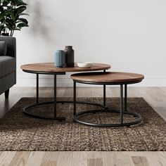 two tables sitting on top of a wooden floor next to a gray couch in a living room