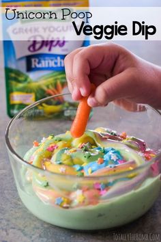 a person is holding a carrot in a bowl with veggie dip on it