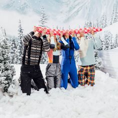 four people are standing in the snow with their hands on top of each others'heads