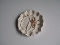 a white plate with two rings on it and some pearls hanging from the ring holder