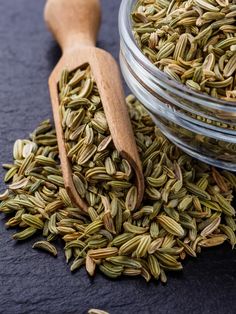 a glass jar filled with seeds next to a wooden spoon