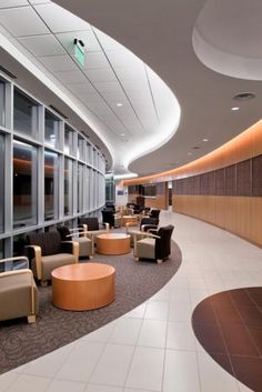 an empty waiting area with chairs and tables in the center, along with large windows