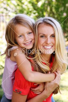 a mother and daughter hugging each other in the park