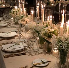 a long table is set with white flowers and candles for an elegant dinner or party