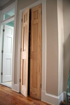 an empty room with two wooden doors and hard wood flooring on the side wall