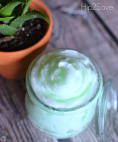 a potted plant sitting next to a jar filled with green cream on top of a wooden table