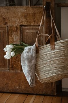 a basket hanging from a door with flowers in it