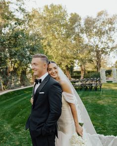 a bride and groom pose for a photo in front of an outdoor ceremony area at their wedding