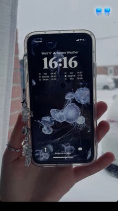 someone is holding up their cell phone with the screen showing jellyfish in the water