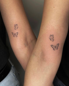 two people with tattoos on their arms holding each other's hands and one has a butterfly tattoo on the arm