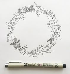 a pen sitting on top of a piece of paper next to a drawing of a wreath