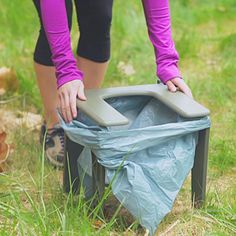 a woman is picking up trash in the grass