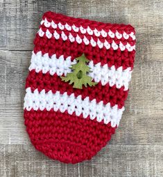 a red and white crocheted bag with a green tree on the front pocket