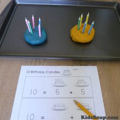 two birthday candles are placed on a sheet of paper next to a tray with a cake