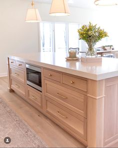 a large kitchen with an island in the middle and two lights hanging from the ceiling