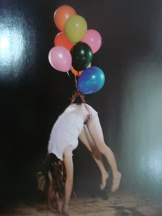 a girl is upside down with balloons in the air