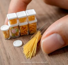 miniature pasta in small containers with one being cut by a pair of scissors on a wooden table