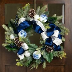 a wreath with blue and white ornaments hanging on a door