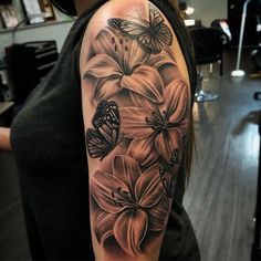 a woman's arm with flowers and butterflies on the back of her shoulder, in black and white