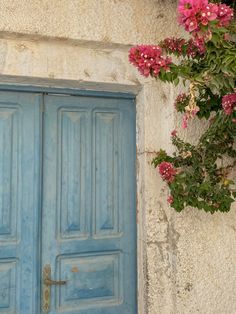 a blue door with pink flowers hanging from it