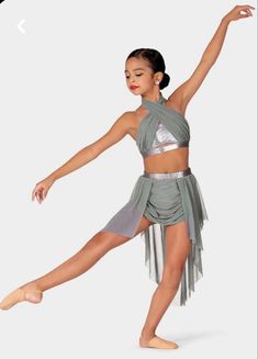 a young woman in a silver skirt and top is dancing with her arms spread out