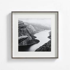 a black and white photo hanging on the wall next to a wooden frame with a lake in it