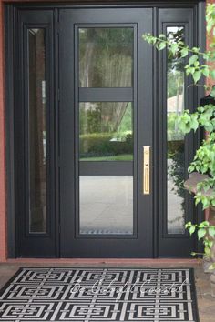 the front door is black and has an intricate design on it, along with a potted plant