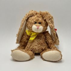 a brown stuffed animal with a yellow ribbon around its neck and ears, sitting on a white surface