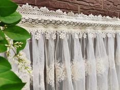 white lace curtains hanging on the side of a brick building