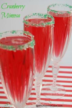 three wine glasses filled with cranberry mimosa on a red and white striped tablecloth