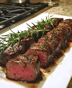 some meat is sitting on a white plate and garnished with green sprigs