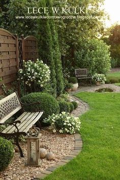 a wooden bench sitting in the middle of a lush green yard with flowers and bushes