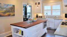 a large kitchen with white cabinets and wood counter tops, along with an island in the middle