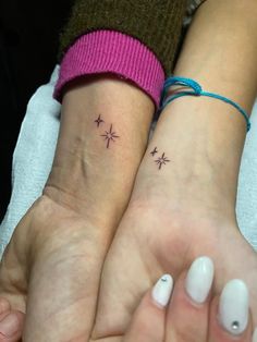 two people with matching tattoos on their wrists, one has a star and the other has a cross