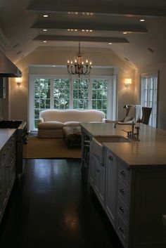 a large kitchen with an island and chandelier hanging from the ceiling