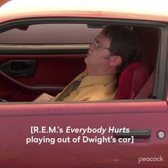 a man sitting in the driver's seat of a red car with an interesting quote on it