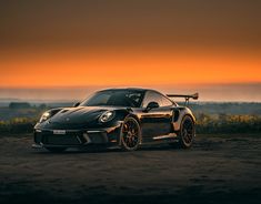 a black sports car parked in front of a sunset