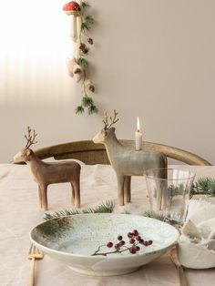 two deer figurines sitting on top of a table next to a glass bowl