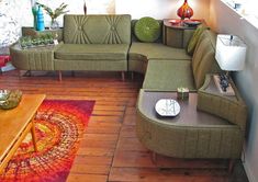 a living room with green couches and red rugs on the wooden flooring