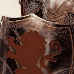 a close up of a metal shield with a lion on it's side and a knight in the background