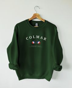 PRODUCT DETAILS & SIZING Colmar, in the Alsace region, is famed for its well-preserved medieval old town, colorful half-timbered houses, and its role as the hometown of sculptor Bartholdi, creator of the Statue of Liberty. Our Colmar sweater is available in multiple different colors. Made from high-quality materials, this sweater features a classic design with a modern twist. Colmar sweater fits both men and women perfectly, and you can go a size up if you want a looser fit. This sweatshirt is a unisex heavy blend crewneck sweatshirt with pure comfort. These garments are made from polyester and cotton.  - 50% cotton, 50% polyester   - Medium-heavy fabric (8.0 oz/yd² (271.25 g/m - Loose fit   - Sewn-in label   - Runs true to size   SHIPPING AND PRODUCTION TIME   - 2-7 working days.   CARE I New Zealand Flag, Coimbra Portugal, England Shirt, Oxford England, Magic City, Birmingham Alabama, Sweater Fits, Trieste, Porto Portugal