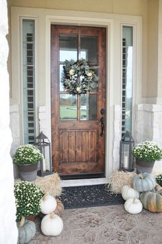 the front door is decorated with pumpkins and flowers