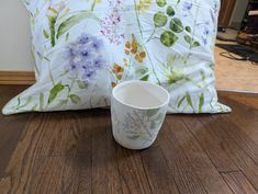 a coffee cup sitting on top of a wooden floor next to a pillow and pillows