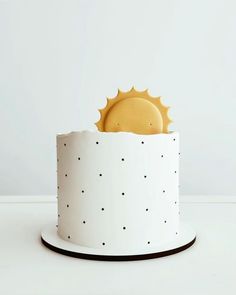 a white and black cake with a sun decoration on top