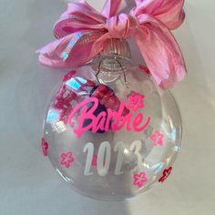 a bauble ornament with a pink bow on the top that says barbie